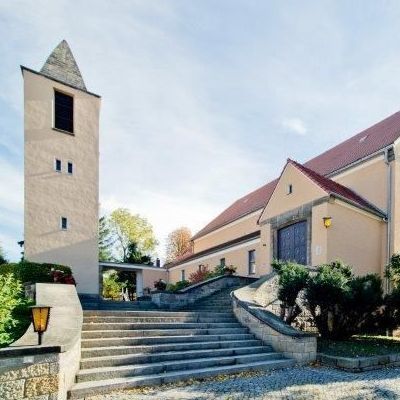 Dachdetail mit Solarpanels, Giebelfenstern und Satellitenschüssel.
