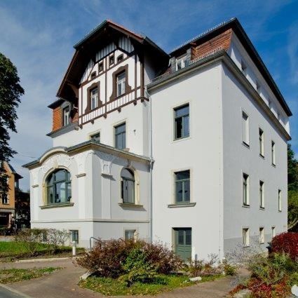 Fassadenausschnitt mit Balkonbrüstung und Regenrinne.