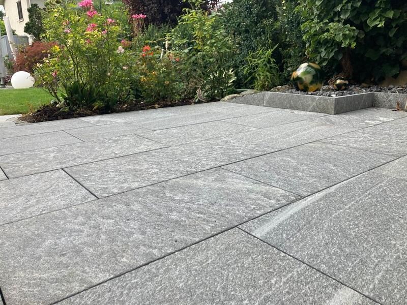 Ein Innenhof mit einem Brunnen und Blumen im Hintergrund.