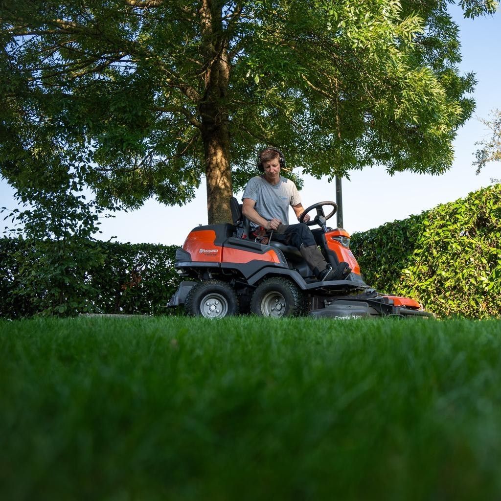 Ein Mann fährt mit einem Rasenmäher über einen üppigen grünen Rasen.