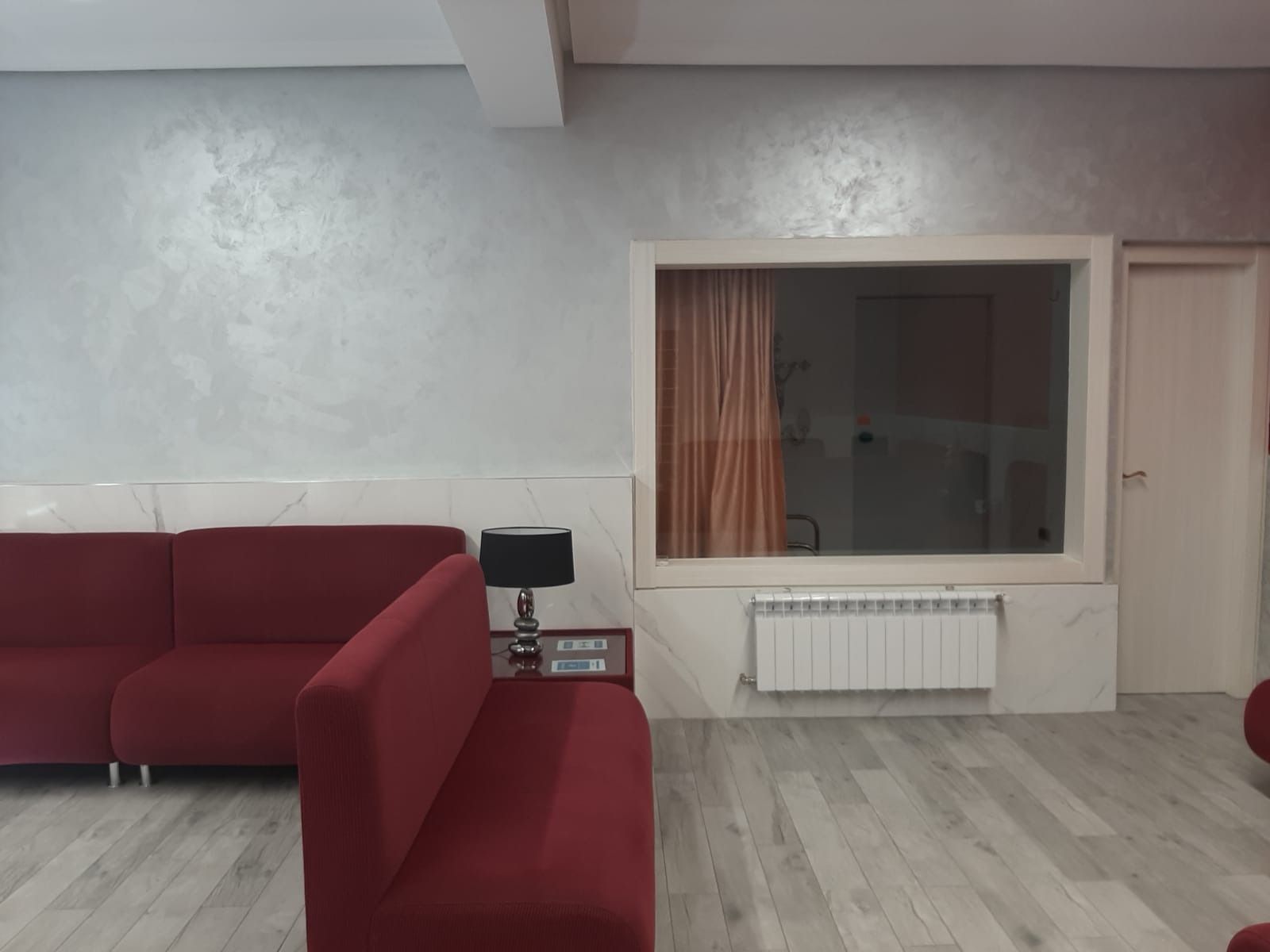 Una sala de estar con un sofá rojo y una gran ventana.