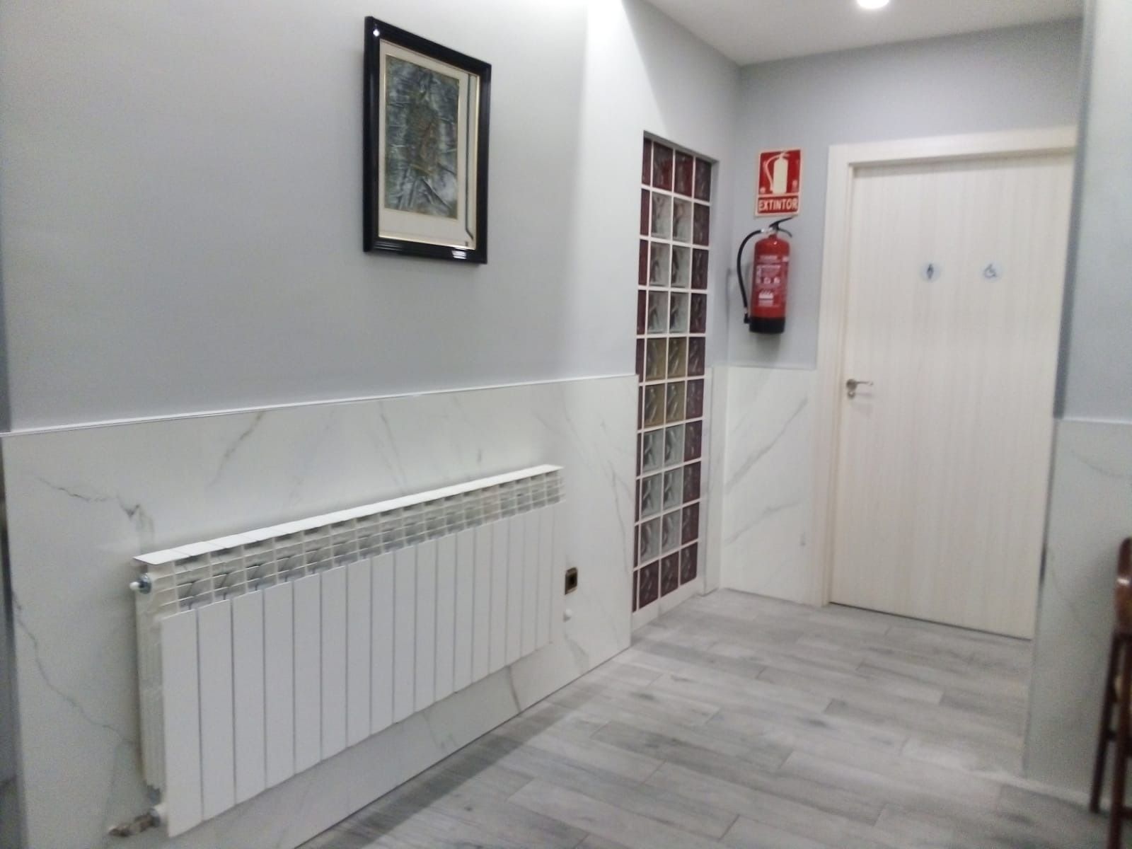 Un pasillo con un radiador en la pared y un extintor en la pared.