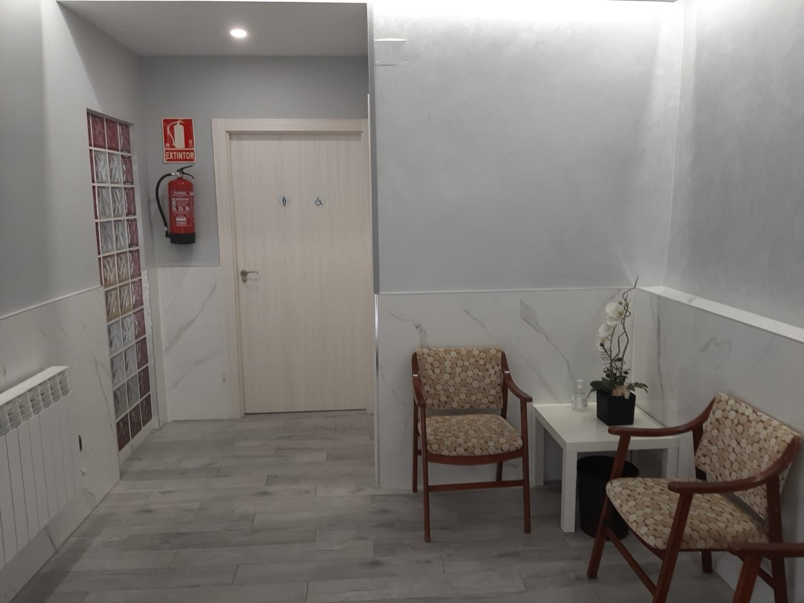 Hay dos sillas y una mesa en el pasillo.
