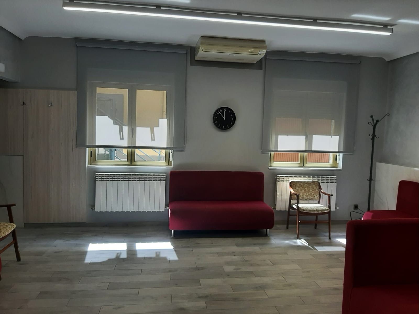 Una sala de estar con un sofá rojo y un reloj en la pared.