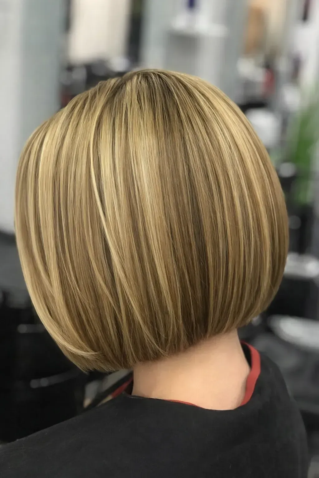 Un elegante corte de pelo bob rubio a la altura de la barbilla, visto desde atrás, con sutiles reflejos.
