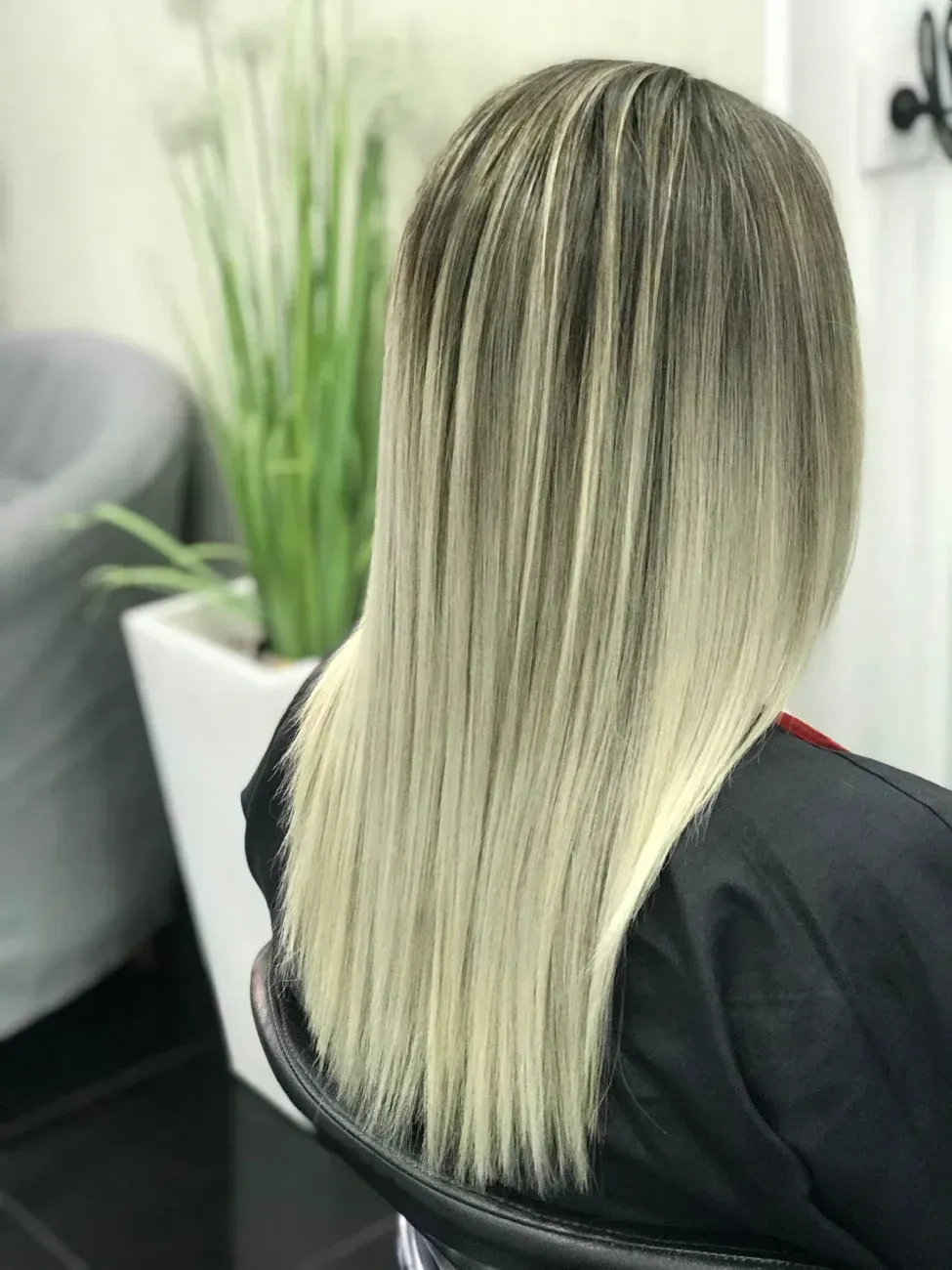 Una persona con cabello castaño largo y ondulado con reflejos color caramelo, vista de espaldas.