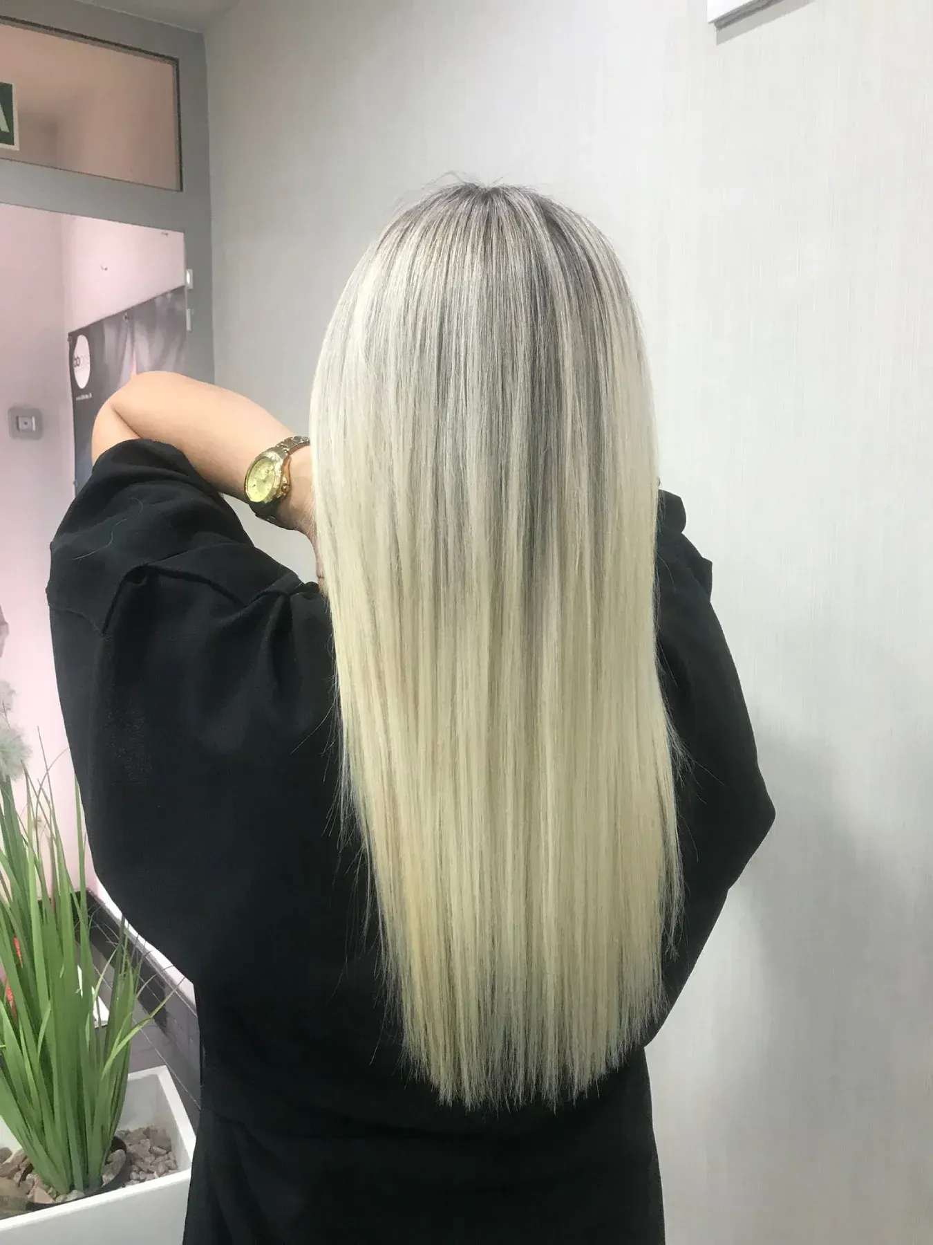 Una persona con un elegante corte de pelo bob rubio miel con sutiles reflejos, vista desde atrás en un salón de belleza.