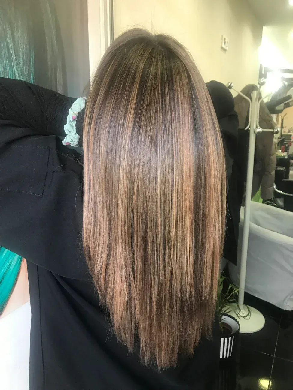 Vista posterior de una melena ondulada a la altura de los hombros con mechas balayage rubio miel.