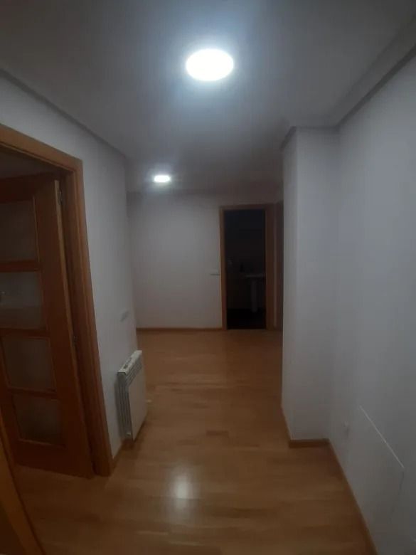 Un pasillo con suelos de madera y paredes blancas.