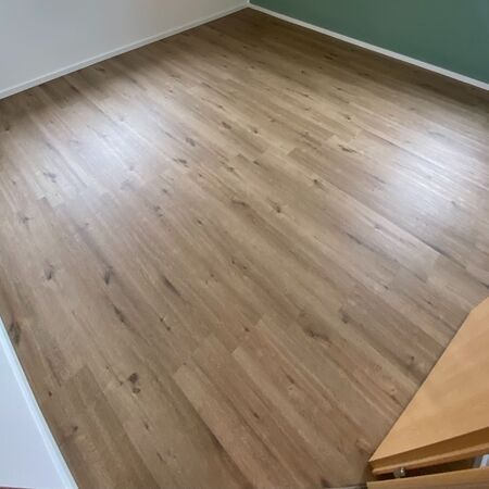 Holzdielenboden in einem Raum mit weißen und grünen Wänden.