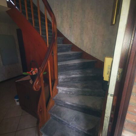 Holztreppe mit grauen Stufen und braunem Geländer.