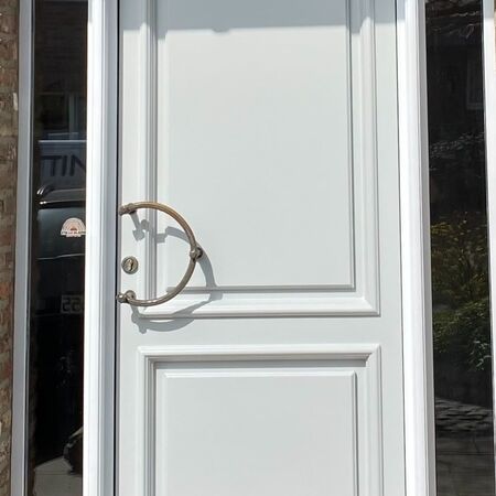 Weiße Eingangstür mit bronzefarbenen Beschlägen und Seitenfenstern.