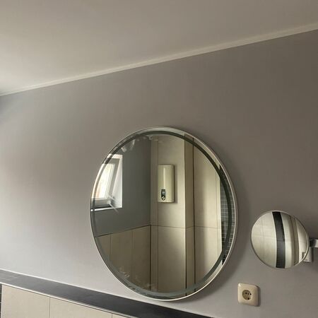 Ovaler Spiegel an grauer Wand