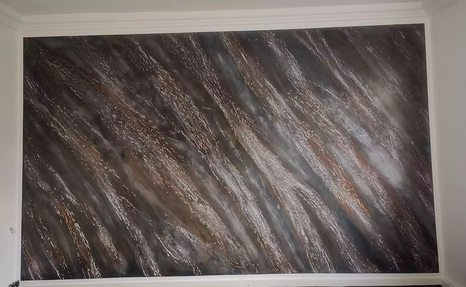 Die Wand ist mit wirbelnden dunkelbraunen, silbernen und goldenen Metallic-Mustern bemalt.