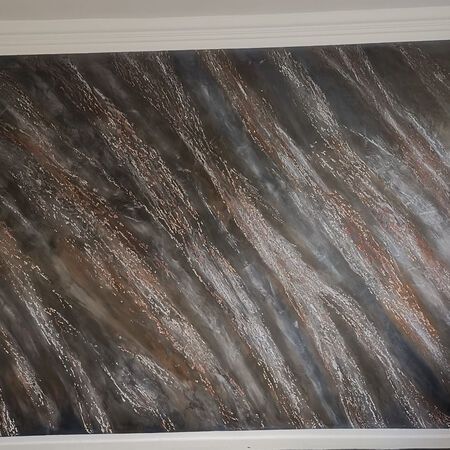 Die Wand ist mit einem strukturierten Muster in Braun-, Grau- und Silbertönen mit diagonalen Strichen bemalt.