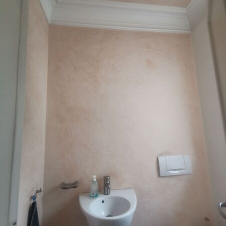 Kleines Badezimmer mit pfirsichfarbenen, strukturierten Wänden, weißen Armaturen und einer weißen Zierleiste.