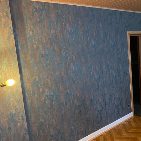 Wand mit strukturierter blauer und kupferfarbener Farbe.