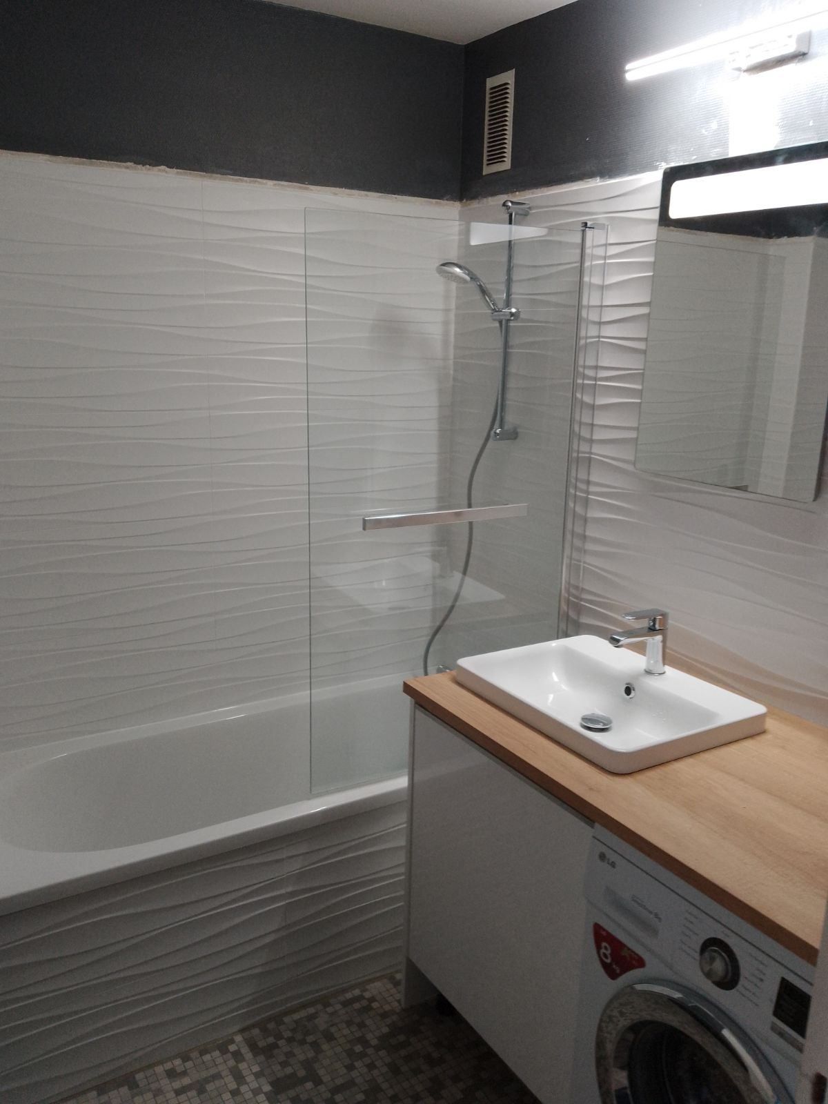 Une baignoire avec une paroi et un meuble vasque