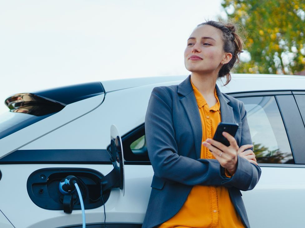 Une jeune femme qui attend que son véhicule électrique soit rechargé