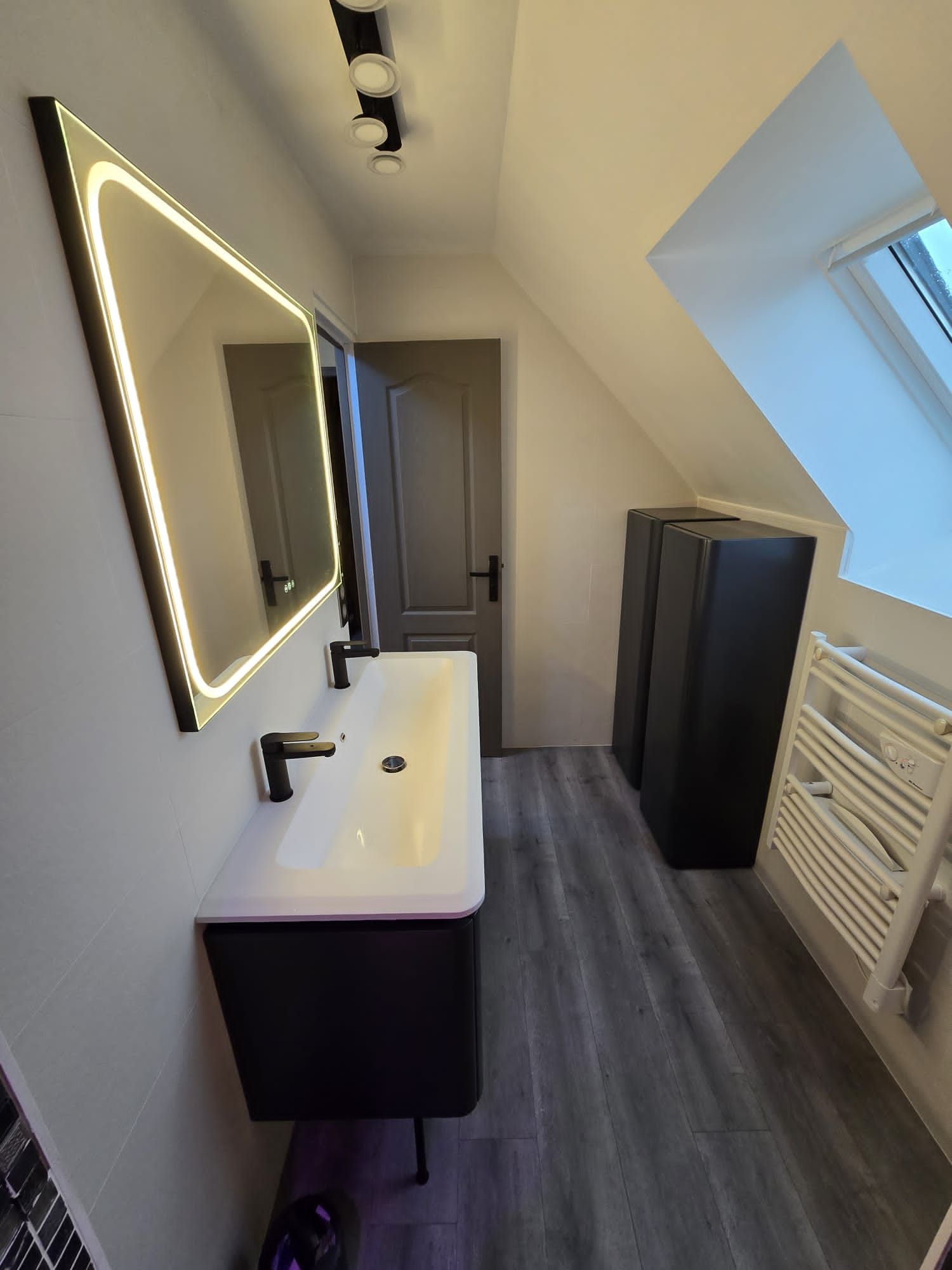 Un meuble double vasque avec un miroir éclairé