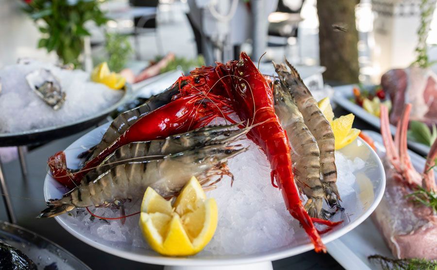 Ein Teller mit Garnelen auf Eis und Zitronenscheiben auf einem Tisch.