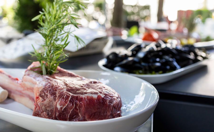 Ein Stück rohes Fleisch liegt auf einem weißen Teller auf einem Tisch.