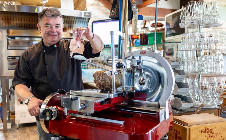 Ein Mann steht in einer Küche vor einer Aufschnittmaschine.