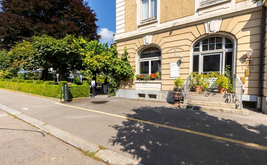 Am Straßenrand steht ein großes Gebäude mit vielen Fenstern.