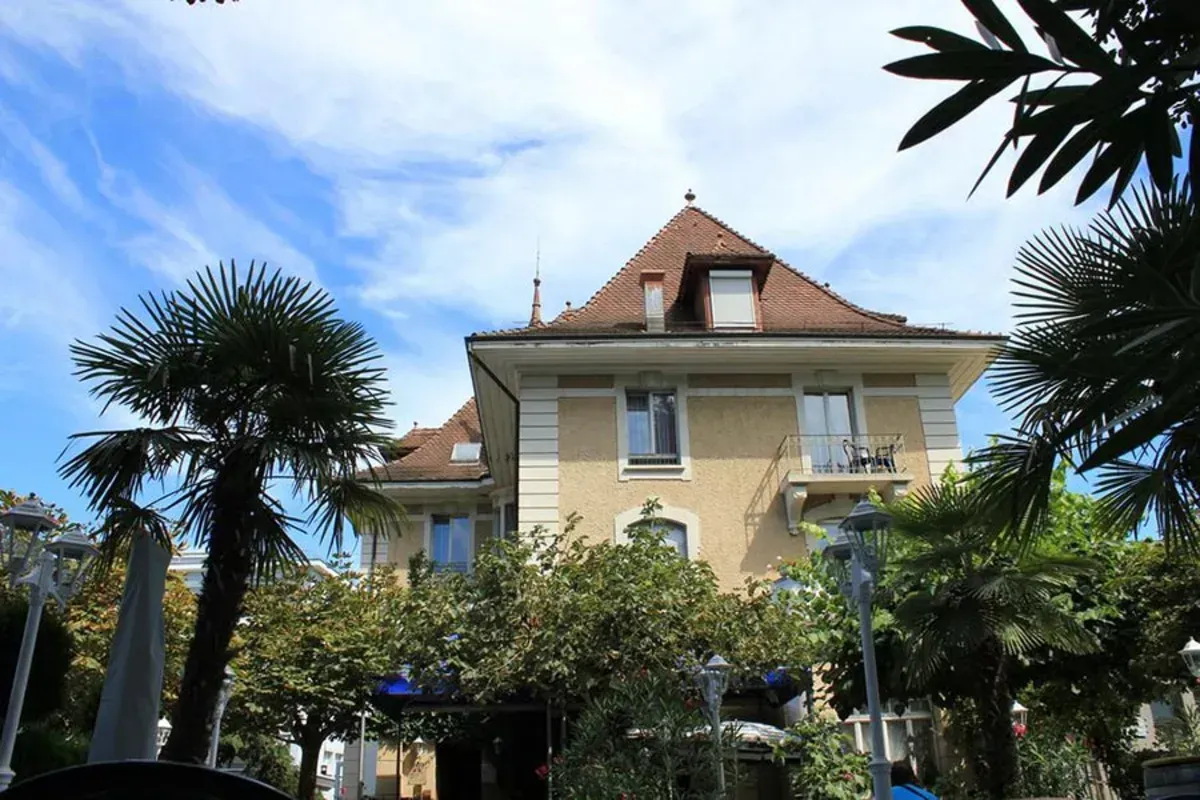 Ein großes Haus mit einem roten Dach ist von Palmen umgeben