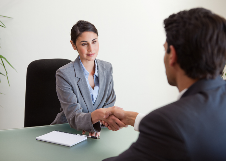 Un hombre y una mujer se dan la mano durante una entrevista de trabajo.