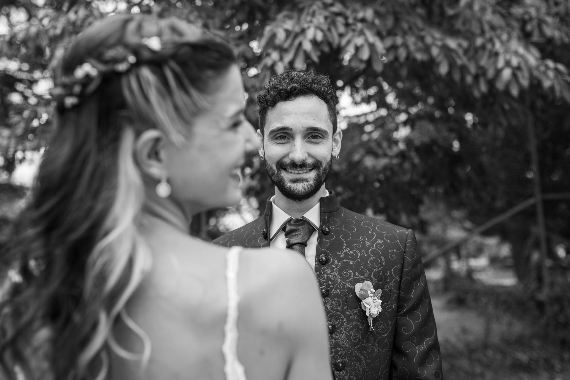 Una novia y un novio se besan delante de una ventana.