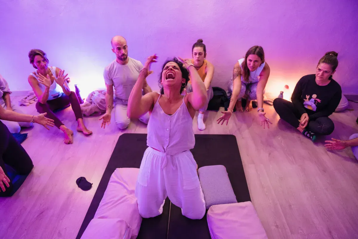 Un grupo de personas está sentada en el suelo en una habitación con luces violetas.