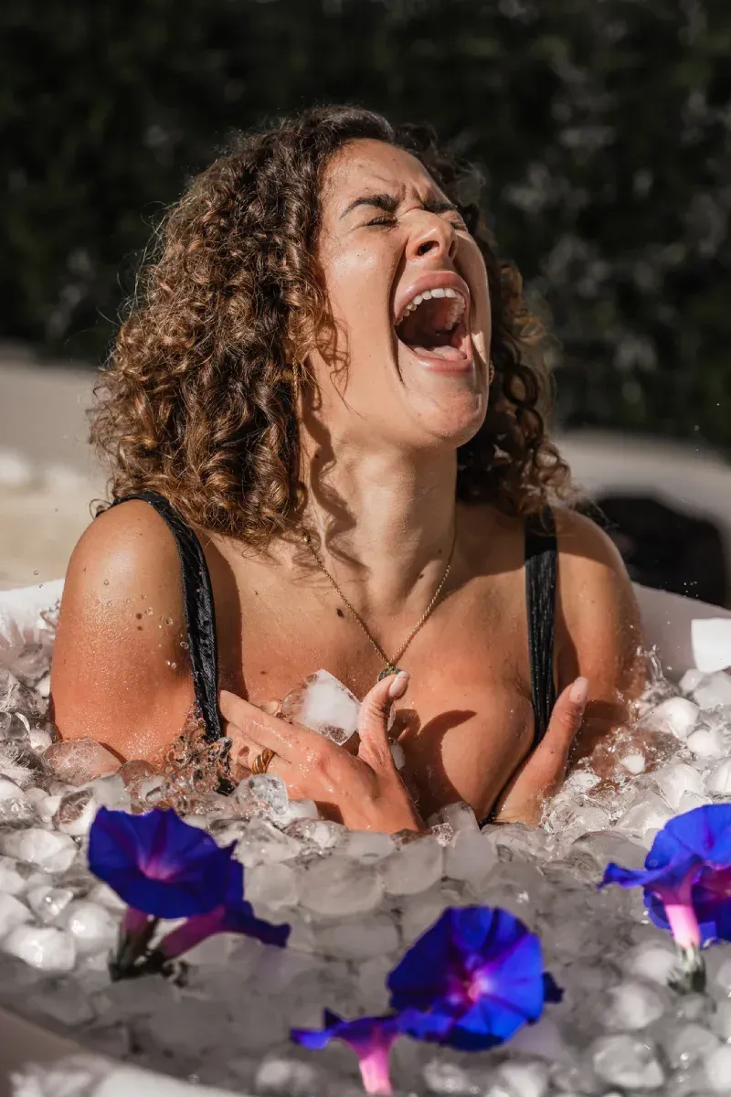 Una mujer está acostada en una bañera llena de hielo y flores.