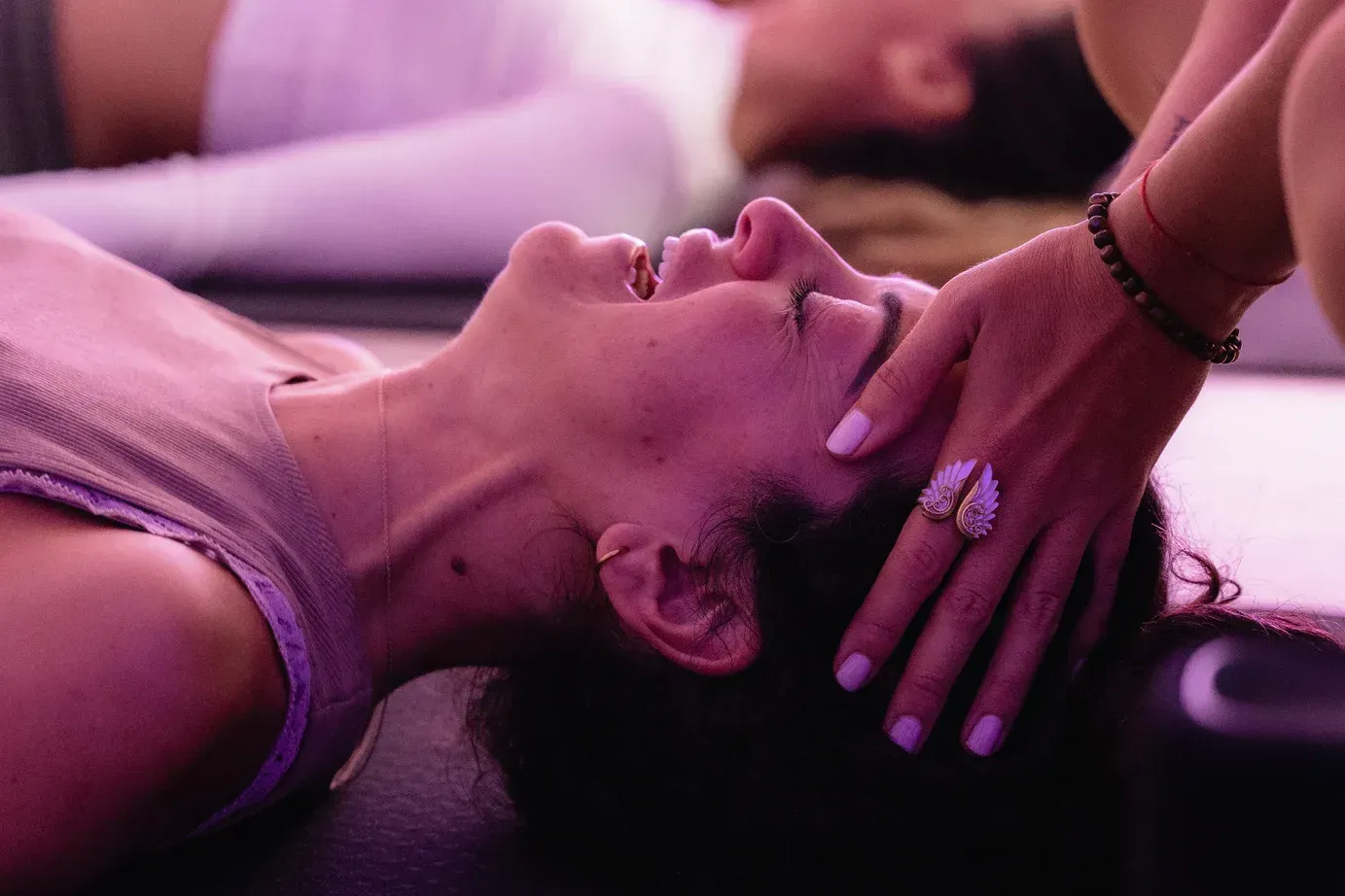 Una mujer está acostada boca arriba con los ojos cerrados y una mano sobre la cabeza.