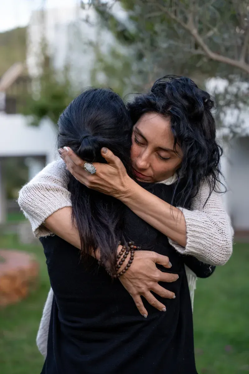 Una mujer abraza a otra mujer en un parque.