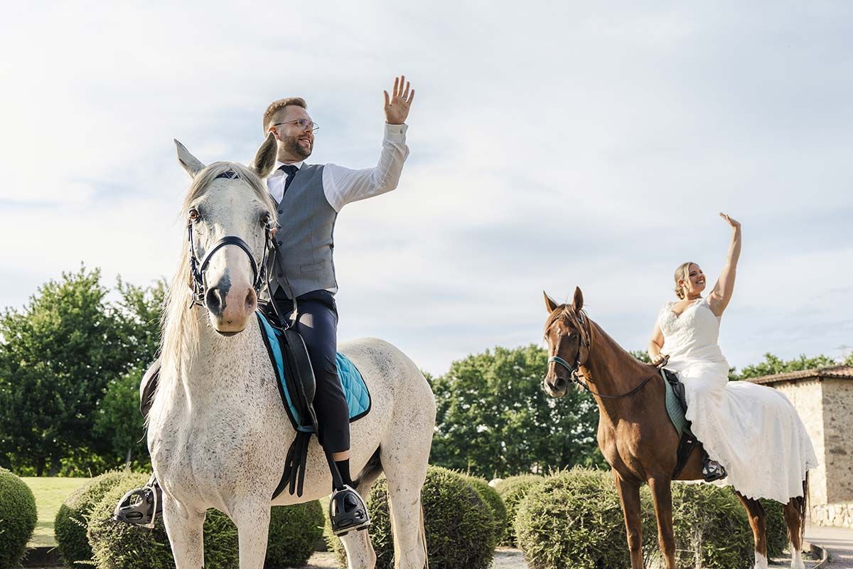 Una novia y un novio montan a caballo el día de su boda.