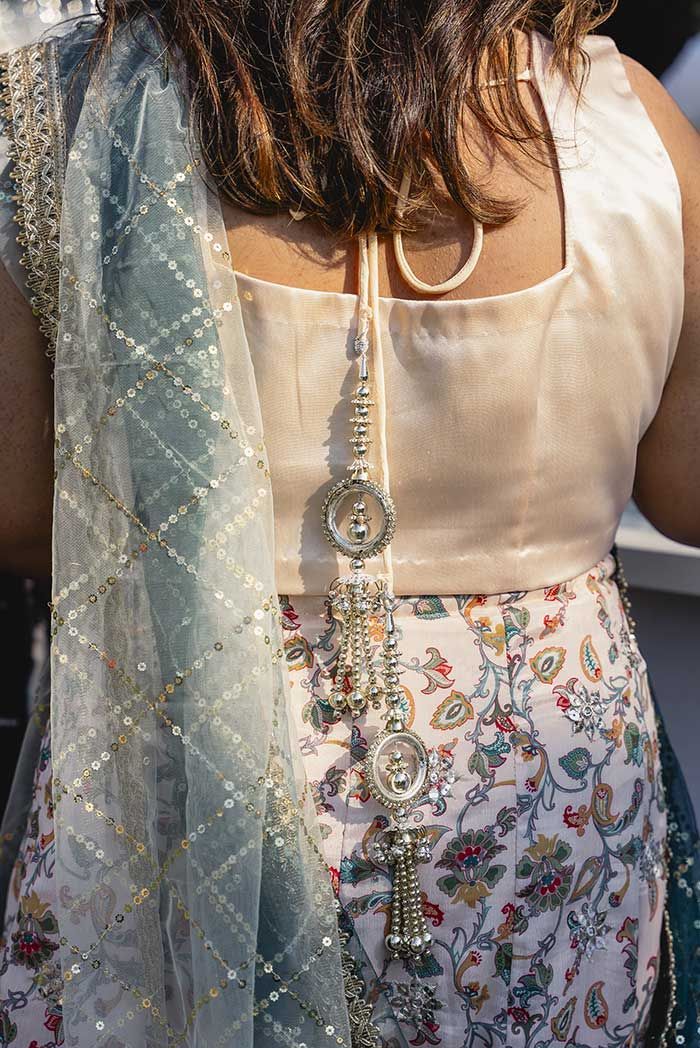 La espalda de una mujer vestida con una blusa blanca y una bufanda azul.