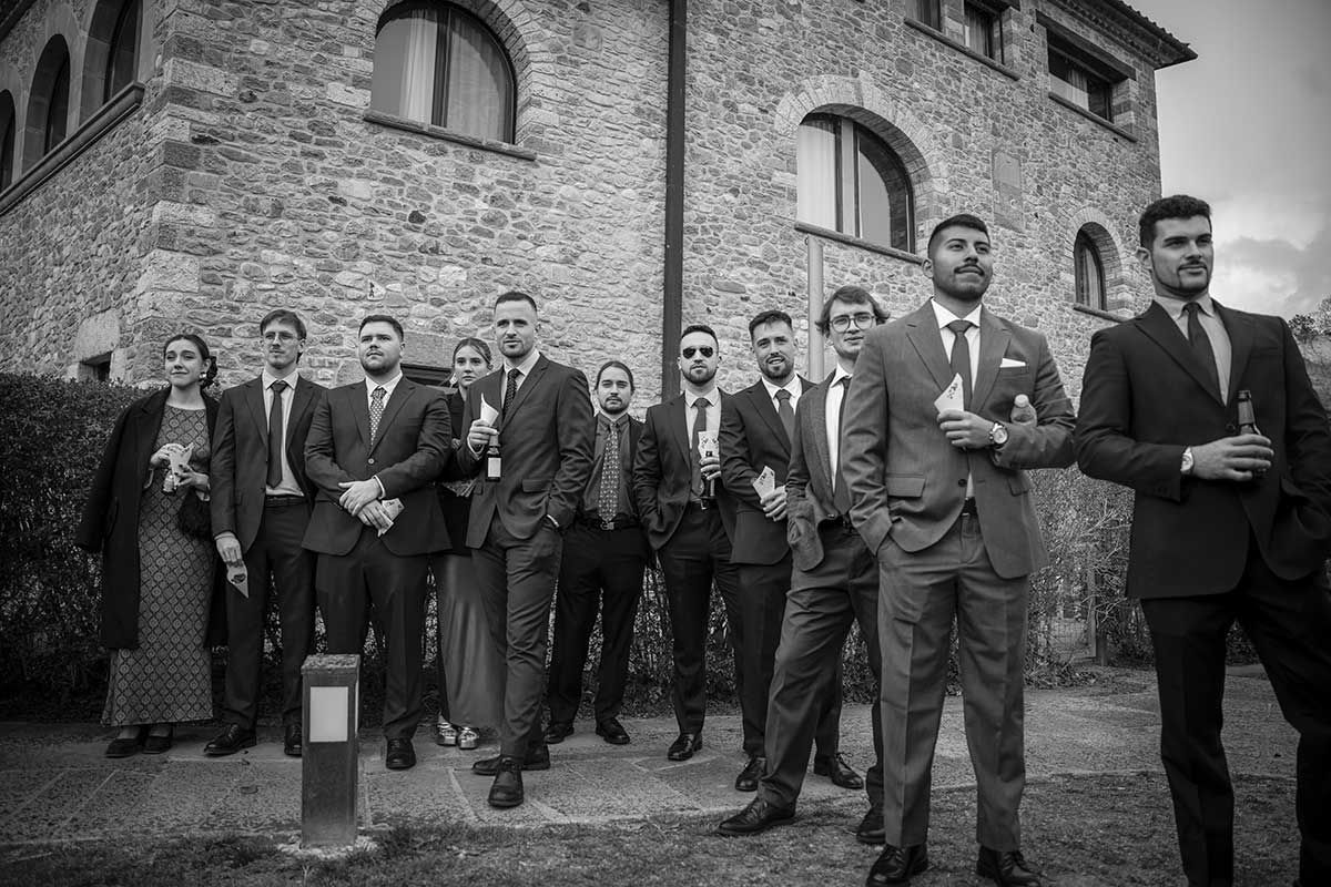 Un grupo de hombres con traje y corbata están de pie frente a un edificio de piedra.