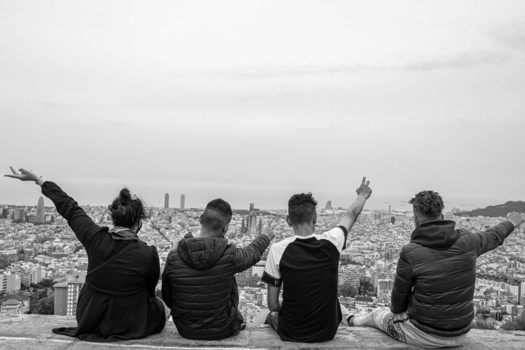 Un grupo de personas está sentado en una cornisa con vistas a una ciudad.