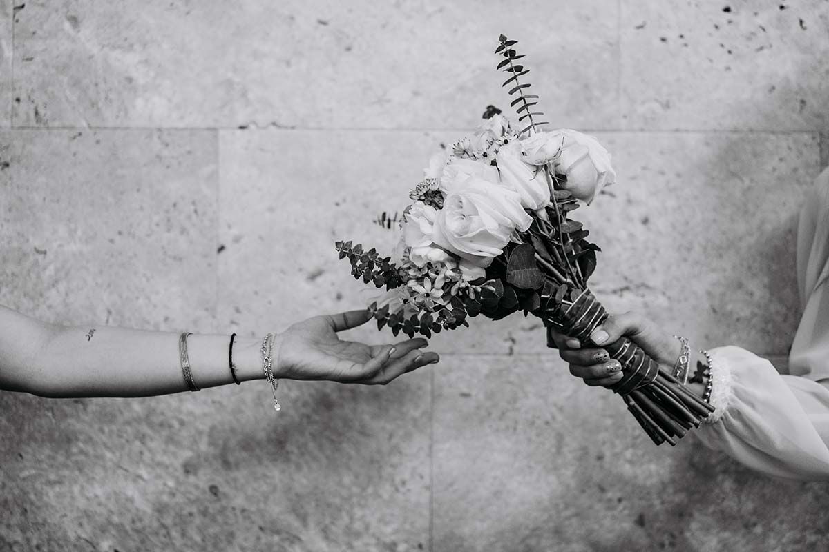 Una mujer le entrega un ramo de flores a otra mujer.