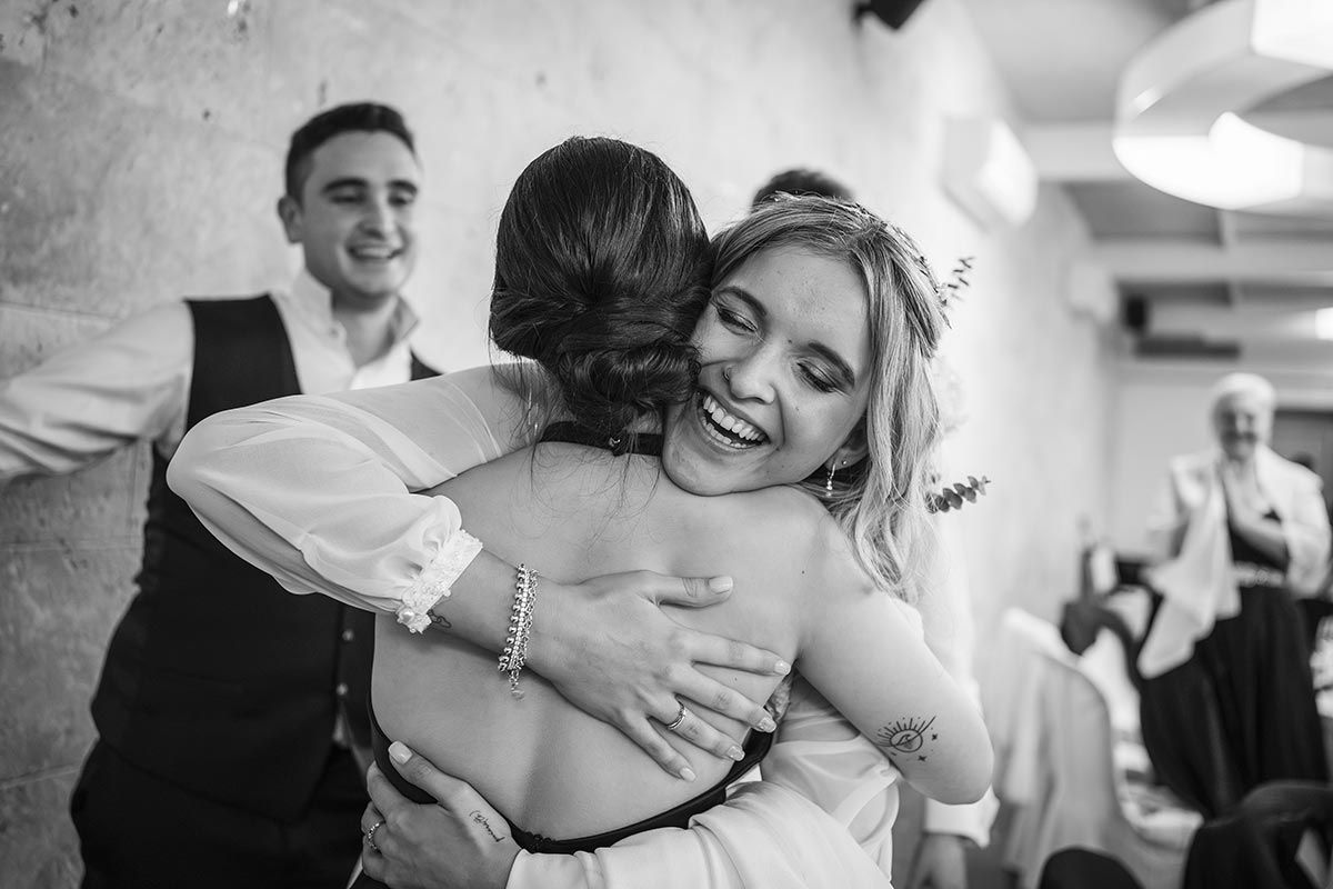Una fotografía en blanco y negro de una novia y un novio abrazándose en una recepción de boda.