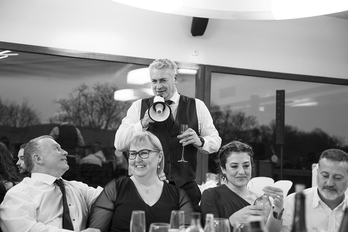 Un grupo de personas está sentado en una mesa con un hombre que sostiene un megáfono.