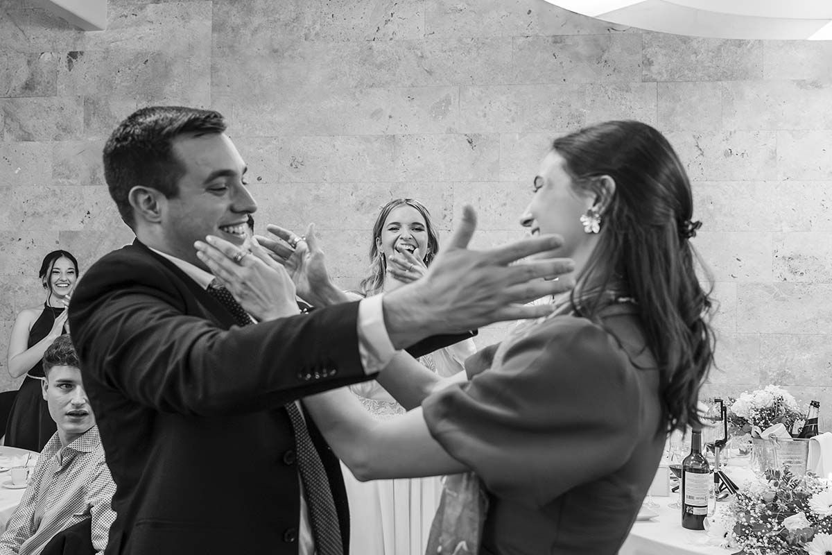 Una fotografía en blanco y negro de un hombre y una mujer bailando en una recepción de boda.