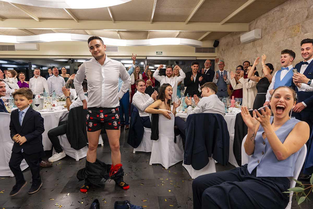 Un hombre en ropa interior está bailando frente a una multitud de personas en una recepción de boda.