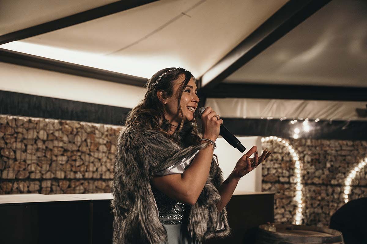 Una mujer con un abrigo de piel está cantando en un micrófono.