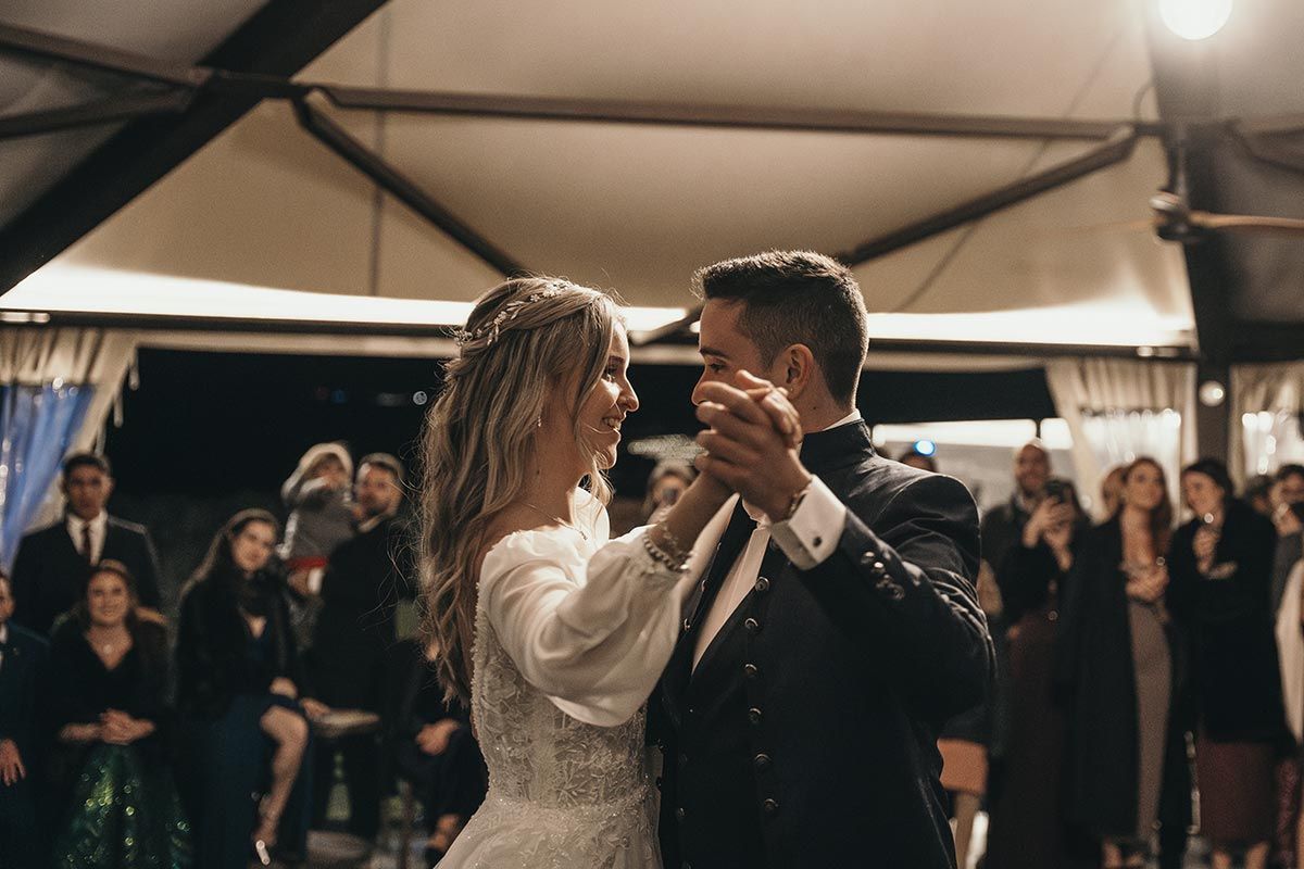 Una novia y un novio están bailando delante de sus invitados a la boda.