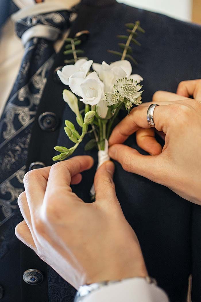 Una mujer está poniendo una flor en la chaqueta de un hombre.
