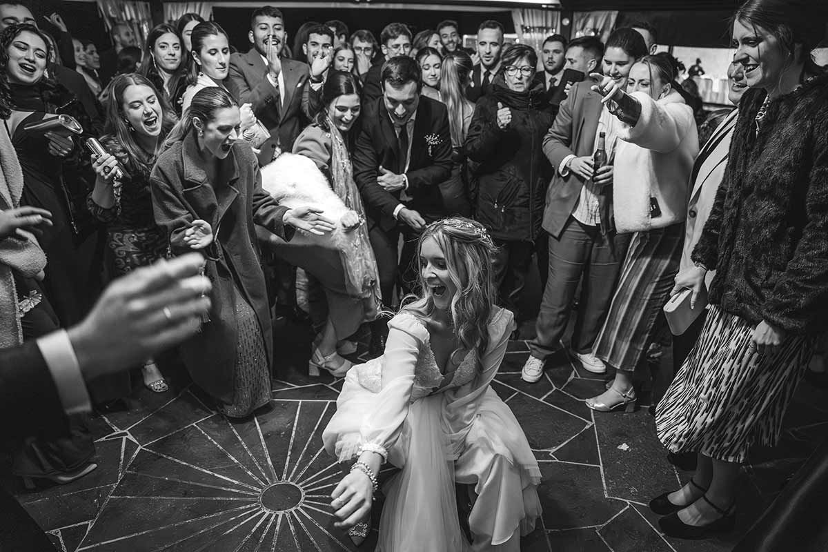 Una mujer con un vestido de novia está bailando delante de una multitud de personas.