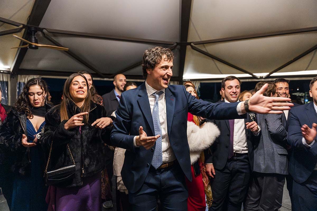 Un hombre con traje y corbata está de pie frente a una multitud de personas.
