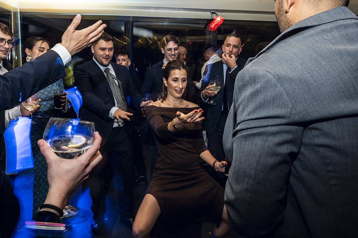 Un grupo de personas está bailando en una fiesta y un hombre sostiene un vaso.